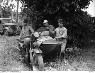 NAURU ISLAND. 1945-09-14. JAPANESE POWS STANDING BY ONE OF THEIR MOTOR CYCLE OUTFITS WHICH IS NOW BEING USED BY MEMBERS OF THE 31/51ST INFANTRY BATTALION - THE OCCUPATION FORCE ON THE ISLAND
