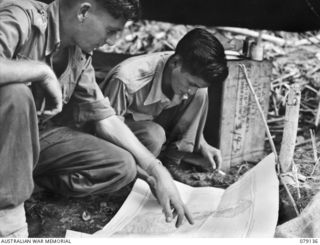 TSIMBA AREA, BOUGAINVILLE ISLAND. 1945-02-19. QX27088 SERGEANT H. HONG CHOY, CHINESE INTERPRETOR, GENERAL HEADQUARTERS, HQ, 2ND AUSTRALIAN CORPS (2) EXPLAINING TO SX23588 LIEUTENANT T. FARRELL (1) ..