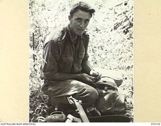 KETOBA, NEW GUINEA. 1944-01-29. VX108714 LANCE CORPORAL C. ROBERTS OF 11TH PLATOON "B" COMPANY, 57/60TH INFANTRY BATTALION CHECKS HIS BRIGADE GEAR BEFORE GOING TO THE ASSAULT