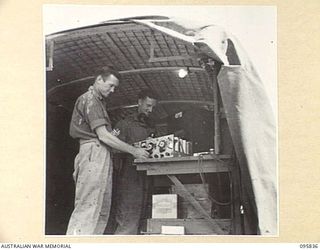 CAPE WOM, WEWAK AREA, NEW GUINEA. 1945-08-30. CRAFTSMAN C.F. ARCHER (1) AND STAFF SERGEANT W.E. DURY (2), REPAIRING WIRELESS TRUCK SPARE PARTS, WIRELESS REPAIRING SECTION, 2/4 ARMOURED REGIMENT ..