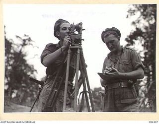 MAMAGOTA AREA, BOUGAINVILLE. 1945-07-22. BOMBARDIER W.A. MOYES (1) AND SERGEANT W.D. COOPER (2) MEMBERS OF 3 SURVEY BATTERY, ROYAL AUSTRALIAN ARTILLERY, TAKING OBSERVATIONS WITH THE THEODOLITE AT ..