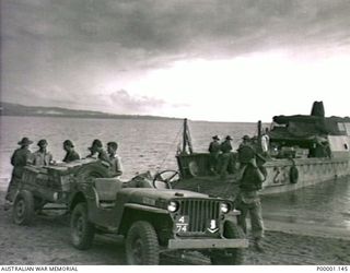 THE SOLOMON ISLANDS, 1945-05. AUSTRALIAN SERVICEMEN UNLOADING STORES FROM A BEACH LANDING CRAFT INTO A JEEP TRAILER AT NORTH BOUGAINVILLE. (RNZAF OFFICIAL PHOTOGRAPH.)