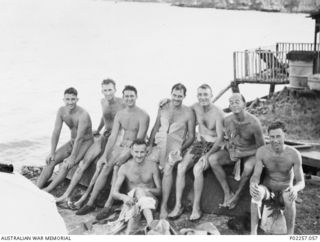 Madang, New Guinea, 1945-08-15. During their celebrations for Victory in the Pacific (VP) Day, RAAF servicemen from Headquarters, RAAF Northern Command (NORCOM), sit on an upturned boat or dinghy ..