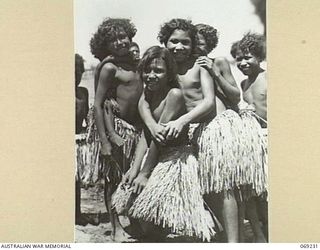 NEW GUINEA. 1942. NATIVE GIRLS IN GRASS SKIRTS AT A VILLAGE VISITED BY PPI. MAJOR GENERAL B.M. MORRIS, DSO, COMMANDING OFFICER, NEW GUINEA LINES OF COMMUNICATION AREA AND THE AUSTRALIAN AND NEW ..