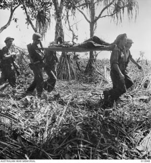 1942-12-28. PAPUA. AN AMERICAN IS IN THE STRETCHER BEARER CREW BRINGING OUT A WOUNDED SOLDIER. THIS PHOTO WAS TAKEN DURING THE ACTUAL FIGHTING. (NEGATIVE BY G. SILK)