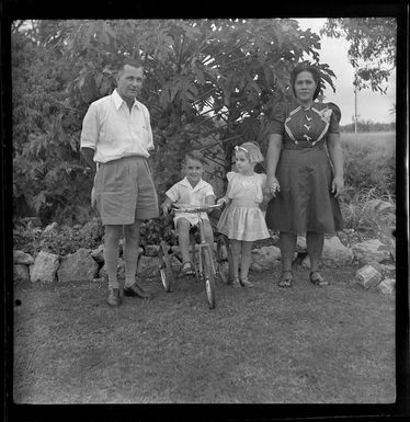 Lee family in garden, including boy on tricycle, Fiji