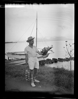 Neil Hilton holding flowers and a bag of citrus fruit, Papeete, Tahiti