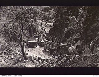 REINHOLD HIGHWAY, NEW GUINEA, 1943-08-31. NATIVES CLEANING THE BENCH ON THE ROAD AT THE 26 MILE POINT