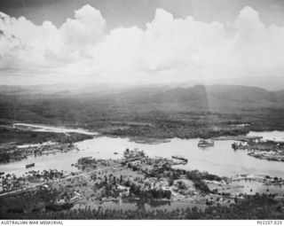 Madang, New Guinea, 1945-10. Aerial view of Madang Harbour, showing two ships at anchor and in the background (left) an airstrip