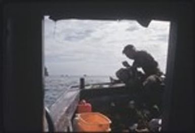 Fishing: giant clams (Tridacninae) on a boat, man holding on up in stern