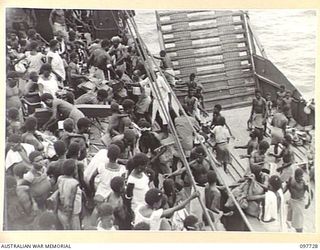 KAHILI, BOUGAINVILLE. 1945-10-02. 350 NATIVES WHO WERE EVACUATED FROM THE BUIN AREA TO FAURO ISLAND BY THE JAPANESE RETURNED TODAY ON THE 300 TON VESSEL NEENA. THEY ARE SHOWN GOING OVER THE SIDE OF ..