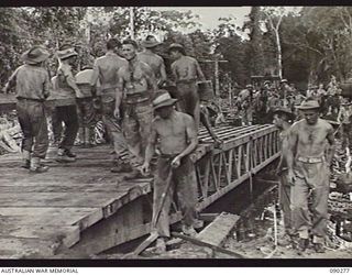 BOUGAINVILLE. 1945-03-30. ENGINEERS OF 15TH FIELD COMPANY, ROYAL AUSTRALIAN ENGINEERS, LAYING DECKING ON A NEWLY CONSTRUCTED GIRDER BRIDGE. IT TOOK THREE HOURS TO REMOVE THE 12 TON BRIDGE AND ..