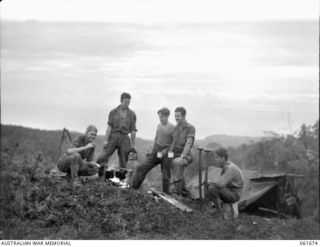 WAREO, NEW GUINEA. 1943-12. TROOPS OF THE 26TH AUSTRALIAN INFANTRY BRIGADE GATHERED AROUND A CAMP FIRE FOR AN EVENING CUP OF TEA. THEY ARE: VX50271 PRIVATE C. A. COOPER OF NAR NAR GOON, VIC, (1); ..