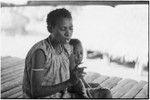 Woman smokes cigarette on veranda with child