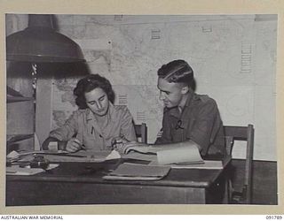 LAE, NEW GUINEA. 1945-05-15. PRIVATE L. MCINTYRE (1), WORKING FOR THE DEPUTY DIRECTOR OF MEDICAL SERVICES, HEADQUARTERS FIRST ARMY, RECEIVES INSTRUCTION IN HER NEW JOB FROM STAFF SERGEANT G. ..