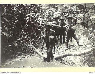 WEBER POINT, MALALAMAI, NEW GUINEA, 1944-02-09. MEMBERS OF "B" COMPANY, 30TH INFANTRY BATTALION, FOLLOWING A MUDDY TRACK BETWEEN WEBER POINT AND MALALAMAI. THEY HAVE BEEN ADVANCING FROM ROINJI (2) ..