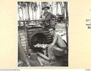 NADZAB, NEW GUINEA. 1943-11. PRIVATE R. BEHRENS AND PRIVATE R.B. SULLIVAN WITH A TRAY OF CAKES AT ONE OF THE IMPROVISED OVENS AT THE CAMP OF THE 10TH FIELD AMBULANCE