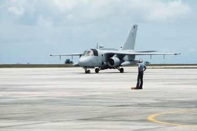 A ground crewman stands ready as the Navy's first operational ES-3A Viking aircraft taxis across an apron. This aircraft is being delivered to Fleet Air Reconnaissance Squadron 5 (VQ-5)