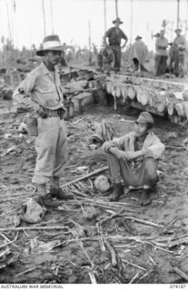 HANSA BAY, NEW GUINEA. 1944-06-21. SERGEANT J.H. IKUTA, ALLIED TRANSLATOR AND INTELLIGENCE SERVICE (1) INTERROGATING A JAPANESE SOLDIER CAPTURED BY MEMBERS OF THE PAPUAN INFANTRY BATTALION