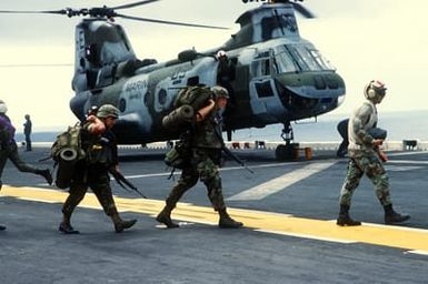 Marines of the 22nd Marine Expeditionary Unit (22nd MEU) are led to a helicopter on the flight deck of the amphibious assault ship USS SAIPAN (LHA-2) during a rehearsal for Operation Sharp Edge. The SAIPAN is on station off the coast of Liberia