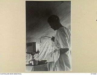 ALEXISHAFEN, NEW GUINEA, 1944-05-11. SX6557 PRIVATE H.C.B. HOLMES (1), USING THE STERILISER AT C SECTION, 2/5TH DENTAL UNIT