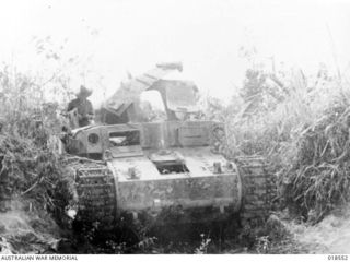 Wewak Area, New Guinea. May 1945. A member of the 6th Division AIF examines a wrecked and rusting Japanese tank, after the fighting had died down on Wewak Peninsula