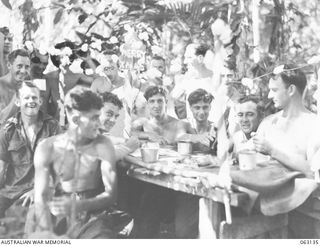 FINSCHHAFEN, NEW GUINEA. 1943-12-25. PERSONNEL OF THE 2/3RD PIONEER BATTALION ENJOY THEIR CHRISTMAS DINNER UNDER PRIMITIVE CAMP CONDITIONS. IDENTIFIED PERSONNEL ARE: NX54526 PRIVATE L. M. KERR (1); ..