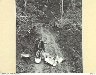 GUY'S POST - MAIN STREAM ROAD, DUMPU AREA, NEW GUINEA. 1944-04-16. V47363 SAPPER J. PARSONS (1), WITH ANOTHER MEMBER OF THE 15TH FIELD COMPANY, ROYAL AUSTRALIAN ENGINEERS WORKING IN TYPICAL COUNTRY ..