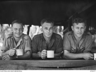 SALAMAUA, NEW GUINEA. 1944-10-01. V43197 PRIVATE J. HOSIE 91); VX131074 PRIVATE G.H. SAUNDERS (2) AND NX167093 PRIVATE J.W. TIERNEY (3) ENJOYING THEIR MORNING TEA IN THE COOKHOUSE, AT HEADQUARTERS ..