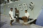 [Three young men standing in front of] Australian destroyer HMAS Anzac (D59), Kavieng wharf, New Ireland, Jun 1964