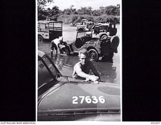 MILNE BAY, NEW GUINEA. 1943-06-26. QX29384 GUNNER J. B. SMITH OF HEADQUARTERS, ROYAL AUSTRALIAN ENGINEERS, 5TH AUSTRALIAN DIVISION, WASHING HIS CAR IN KALOHI CREEK