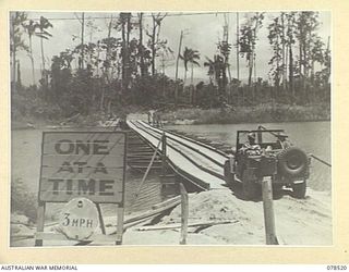 BOUGAINVILLE ISLAND, 1945-01-19. AN AUSTRALIAN ARMY JEEP CROSSING THE OLD FBE BRIDGE ACROSS THE REINI RIVER WHICH IS TO BE REPLACED BY A NEW PERMANENT BRIDGE TO BE BUILT BY THE 5TH FIELD COMPANY