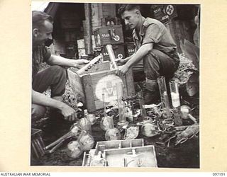 CAPE WOM, NEW GUINEA. 1945-09-27. JAPANESE EQUIPMENT FOUND AT CAPE WOM, BEING SORTED BY PRIVATE L.R. DE VRIES (1) AND PRIVATE K. GAYNOR (2), MEMBERS OF 2/7 FIELD AMBULANCE