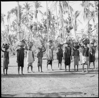 Ten women carrying bags on their heads walking to the Boong, native markets, Rabaul, New Guinea, ca. 1936, 1 / Sarah Chinnery