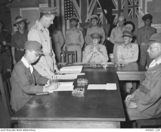 THE SOLOMON ISLANDS, 1945-09-08. LIEUTENANT GENERAL MASATANE KANDA, COMMANDER JAPANESE XVII ARMY, SIGNING THE INSTRUMENT OF SURRENDER AT II AUSTRALIAN CORPS HEADQUARTERS, TOROKINA, BOUGAINVILLE ..