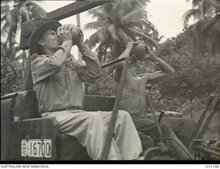 AITAPE, NORTH EAST NEW GUINEA. C. 1944-06. FLIGHT LIEUTENANT J. M. MCPHAIL (LEFT), LINDFIELD, NSW, AND LEADING AIRCRAFTMAN J. W. MORRIS, GLADSTONE, QLD, REFRESH THEMSELVES WITH COCONUT JUICE WHILE ..