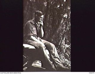 REINHOLD HIGHWAY, NEW GUINEA, 1943-08-31. SX2663 SERGEANT E. E. SMITH, MILITARY HISTORY RECORDER, MILITARY HISTORY SECTION, HAVING A REST DURING THE DESCENT FROM FOX'S GAP TO CENTRE CAMP. THE CLIMB ..