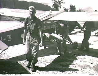 THE SOLOMON ISLANDS, 1945. A WOUNDED AUSTRALIAN SOLDIER ON BOUGAINVILLE ISLAND BEING CARRIED FROM RAAF AUSTER AIRCRAFT A11-3. (RNZAF OFFICIAL PHOTOGRAPH.)