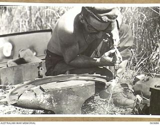 HUON PENINSULA, NEW GUINEA. 1944-01-14. NX135507 CRAFTSMAN R. E. BOUCHER OF THE 209TH LIGHT AID DETACHMENT USING AN OXYACETYLENE CUTTER ON A TANK SPROCKET