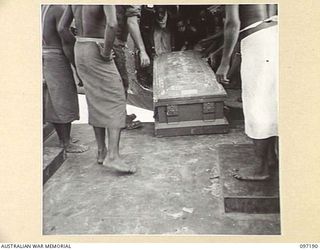 CAPE WOM, NEW GUINEA. 1945-09-27. NATIVES WORKING WITH 2/7 FIELD AMBULANCE, UNLOAD FROM A DOUGLAS AIRCRAFT A CASKET CONTAINING THE BODIES OF AUSTRALIAN SOLDIERS KILLED IN THE MAPRIK AREA