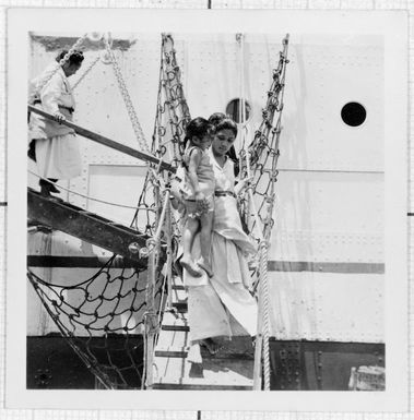 Woman holding a child, disembarking from a boat in Tonga