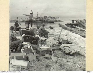 MADANG, NEW GUINEA. 1944-04-24. AN ABLE SEAMAN OF THE RAN SIGNALS THE CORVETTE HMAS BUNDABERG WHICH LATER TOOK A PLATOON OF THE 8TH INFANTRY BRIGADE TO LAND ON SEK ISLAND. IN THE FOREGROUND MEMBERS ..