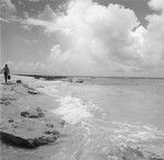 Man walks on beach with equipment, Bikini Atoll area