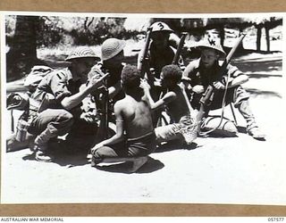 KAIAPIT, NEW GUINEA. 1943-09-25. TROOPS OF THE 2/14TH AUSTRALIAN INFANTRY BATTALION SHOWING THEIR RIFLES TO SOME NATIVE BOYS. THEY ARE, LEFT TO RIGHT:- VX50342 PRIVATE (PTE) H. MURRAY; QX41516 PTE ..