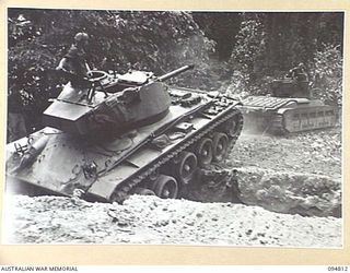 TOROKINA AREA, BOUGAINVILLE, 1945-08-08. AN M24 GENERAL CHAFFEE LIGHT TANK BEING TOWED OUT OF A DITCH BY A MATILDA TANK. IT FAILED TO NEGOTIATE THE OBSTACLE DURING TRIALS CONDUCTED FOR THE WAR ..