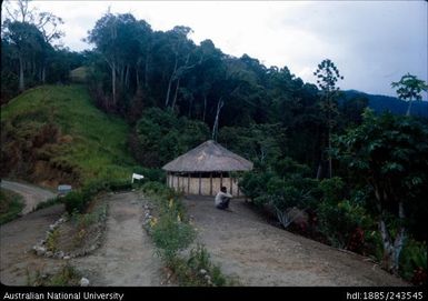 Man seated, house and garden