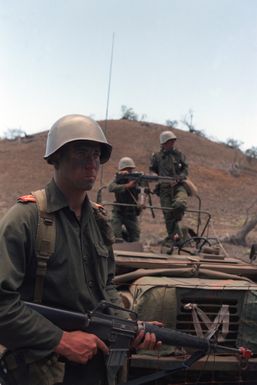 Members of the 1ST Battalion, 27th Infantry, 25th Infantry Division, acting as opposing forces, prepare for an airmobile assault by friendly forces during Exercise OPPORTUNE JOURNEY 4-84 at the Pohakuloa Training Area. The soldier in the foreground is armed with an M16A rifle while the soldier in the background mans an M60 machine gun