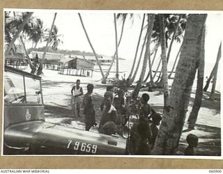 PA PA, PAPUA. 1943-12-02. GENERAL VIEW OF THE VILLAGE LOOKING THROUGH THE COCONUT PALMS, WITH A JEEP AND NATIVE CHILDREN IN THE FOREGROUND