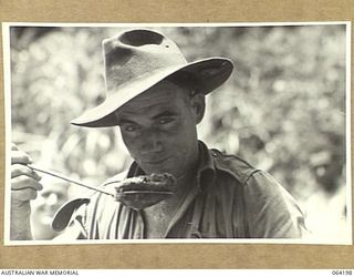 MOUNT PROTHERO AREA, NEW GUINEA. 1944-01-20. QX34529 PRIVATE P.L. MADDEN A COOK OF THE 2/12TH INFANTRY BATTALION TASTING A MEAL WHICH HE IS COOKING FOR THE TROOPS PRIOR TO THE ATTACK ON THE ENEMY ..