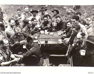 KAIAPIT, NEW GUINEA, 1943-09-22. PERSONNEL OF HEADQUARTERS, 21ST AUSTRALIAN INFANTRY BRIGADE USING A JEEP AS A TABLE DURING A MEAL AND CUPPA. SHOWN ARE - SERGEANT MUSSE (1); CORPORAL RALPH (2); ..